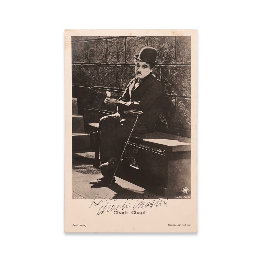 CHARLIE CHAPLIN SIGNED POSTCARD - CITY LIGHTS PROMOTIONAL IMAGE: 5 1/2 x 3 1/2 in (13.8 x 8.8 cm) This remarkable signed postcard features an iconic image of Charlie Chaplin in his most beloved role as "The Tramp," seated on a stone bench holding a flower-a still f