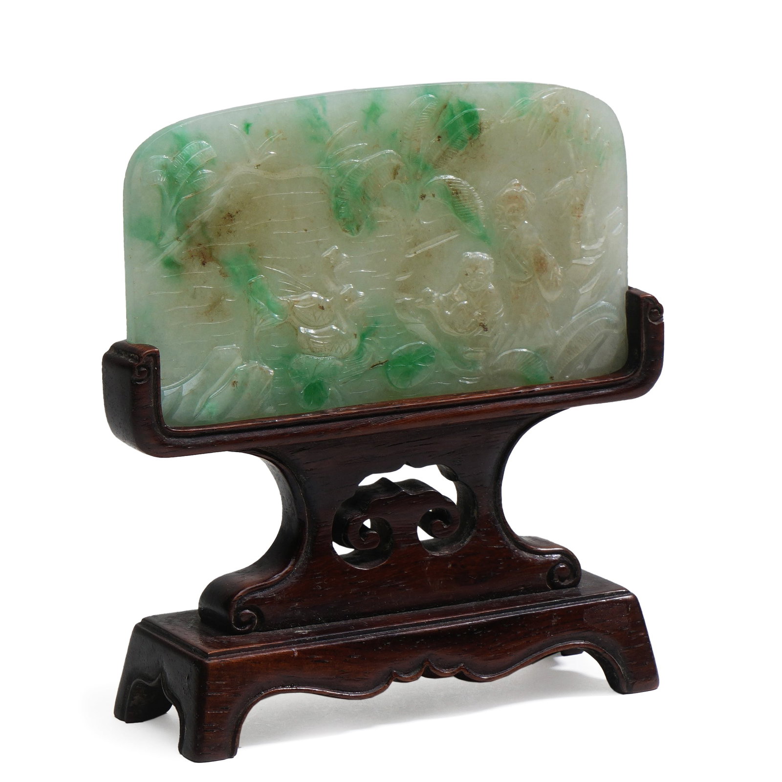 Jadeite Carving (with Wooden Base): H:11.2cm W:10.5cm This is a jadeite carving with a wooden base. The jadeite has a warm texture and emerald green color. There are exquisite carved patterns on the carving, and the craftsmanship is