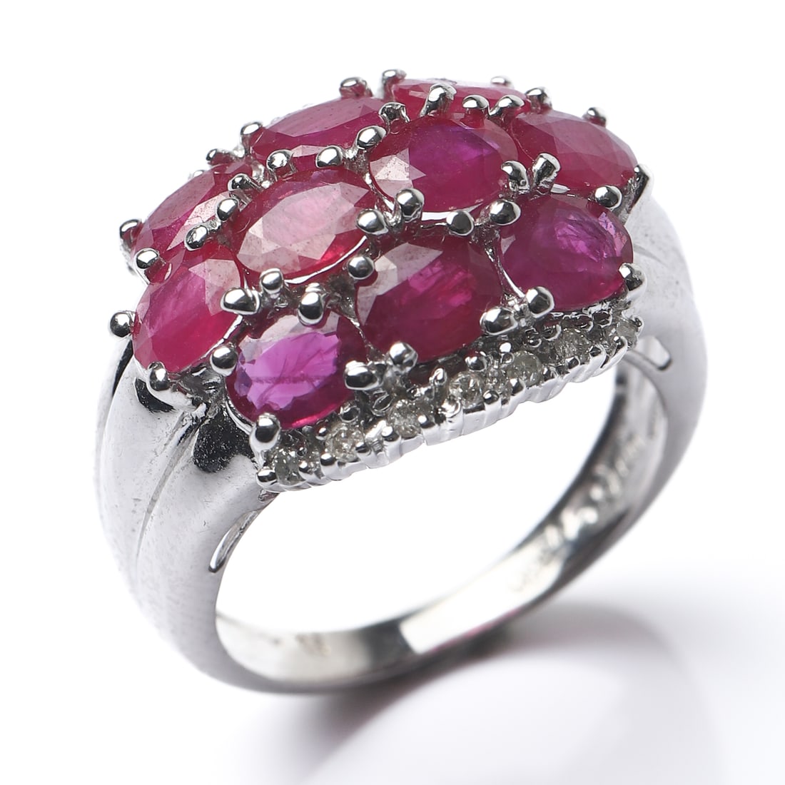 18K GOLD RUBY AND DIAMOND RING: Dimensions Inner diameter: 5/8 in (16.3 mm); Weight: 6.8 g Description This refined ring is crafted in 18k white gold and set with a clustered arrangement of oval-cut rubies forming a softly domed rec