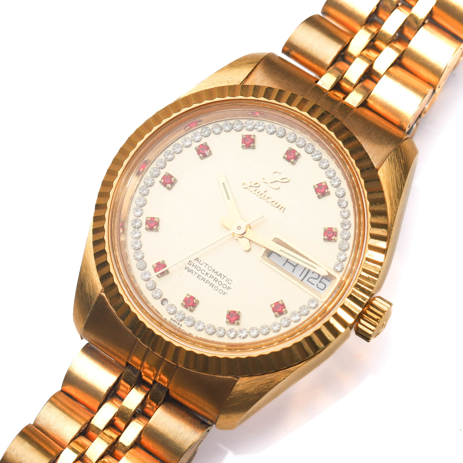 LUBCAM AUTOMATIC GOLD-TONE WRISTWATCH WITH DATE: Dimensions Dial diameter: 1 3/8 in. (34.6 mm) Description This vintage Lubcam automatic wristwatch features a gold-tone case with a fluted bezel and a champagne dial accented by red gemstone hour