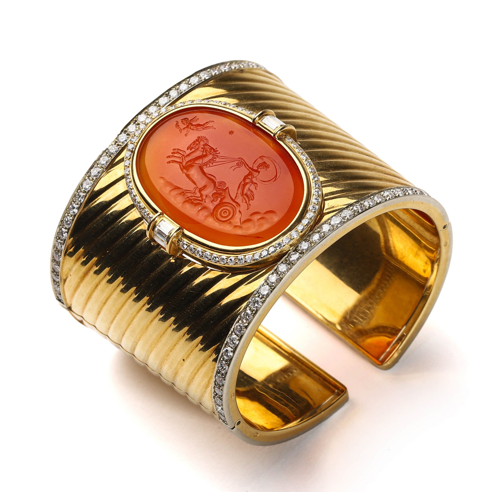 GOLD AND CARNELIAN CUFF BRACELET WITH DIAMONDS, SIGNED D.S. & A.: Dimensions: Interior diameter: 2 3/16 in. (55.3 mm) Weight: 125.3 g A bold and striking wide cuff bracelet crafted in polished fluted gold, centering a finely carved oval carnelian intaglio depicting 