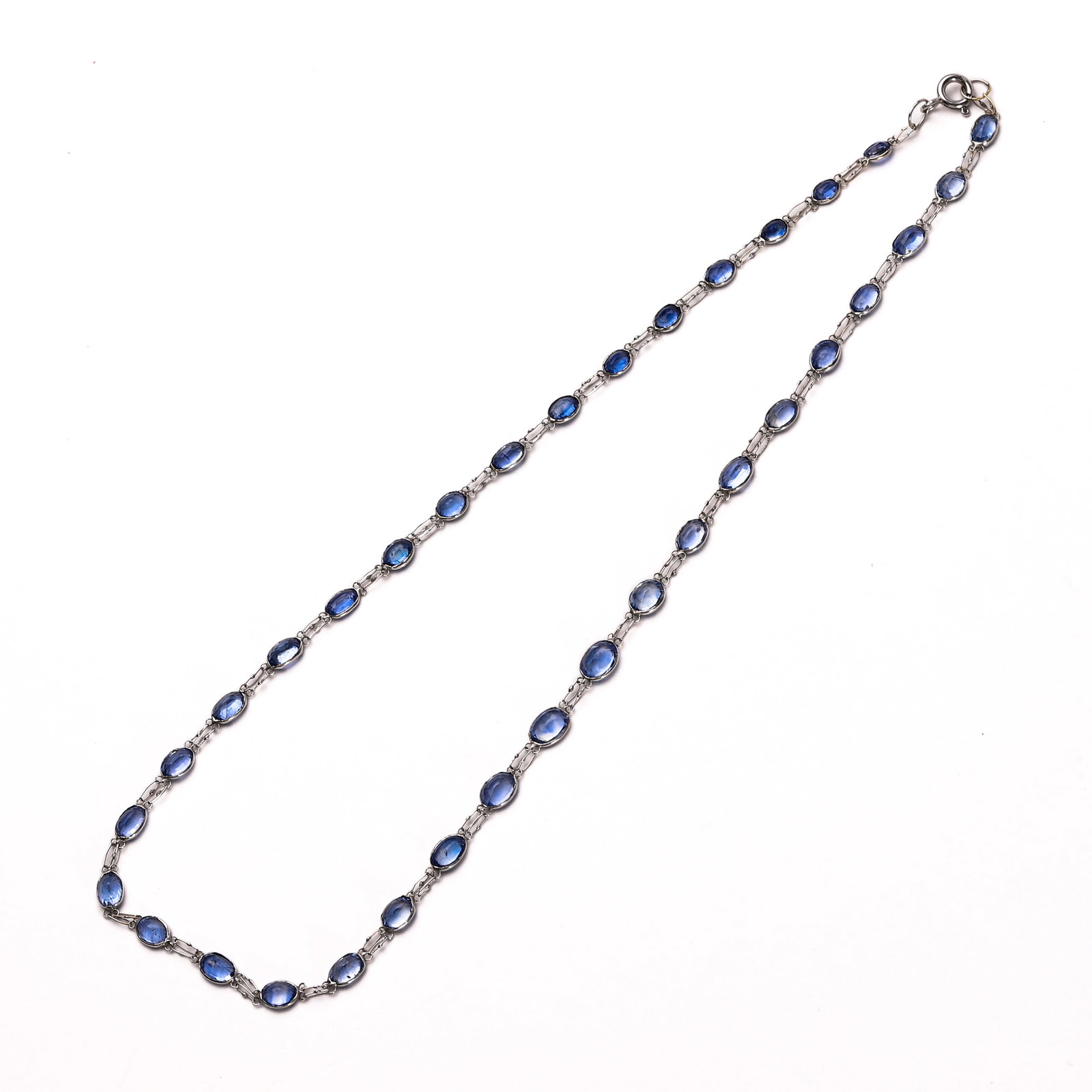 BLUE GEMSTONE AND SILVER NECKLACE: Dimensions: Length: 16 1/2 in. (42 cm); Weight: 5.6 g Description: A delicate necklace composed of faceted oval blue gemstones—likely sapphires or kyanites—each individually bezel-set in silver. T