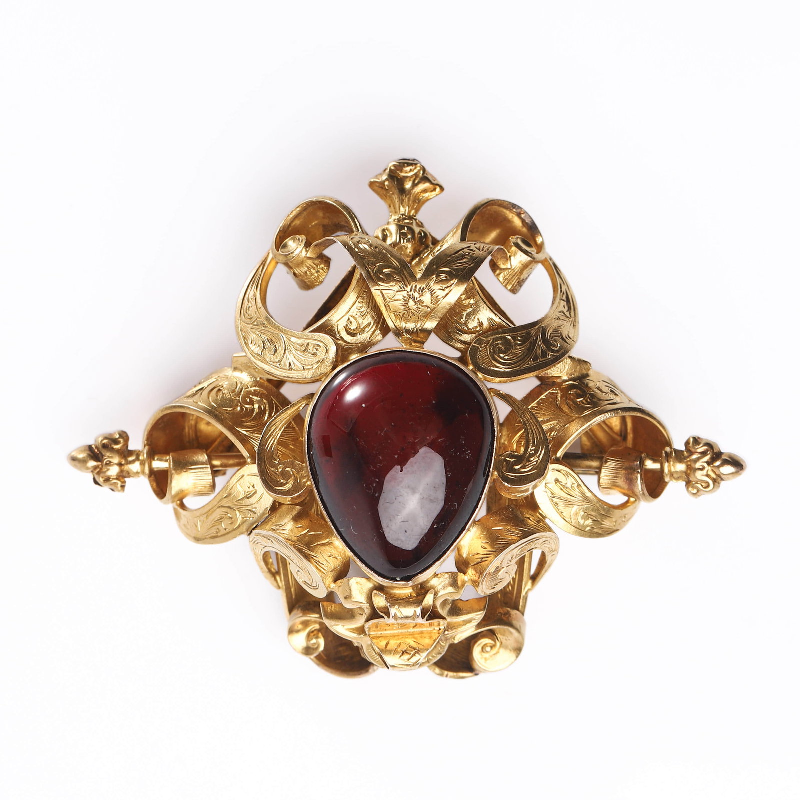 A GOLD BROOCH SET WITH A GARNET CABOCHON.: Dimensions Length 2 3/8 in (6 cm); width 1 13/16 in (4.6 cm); central stone 3/4 × 5/8 in (19.5 × 16.5 mm); weight 15.4 g. Description: The elaborate openwork brooch is finely crafted in gold with