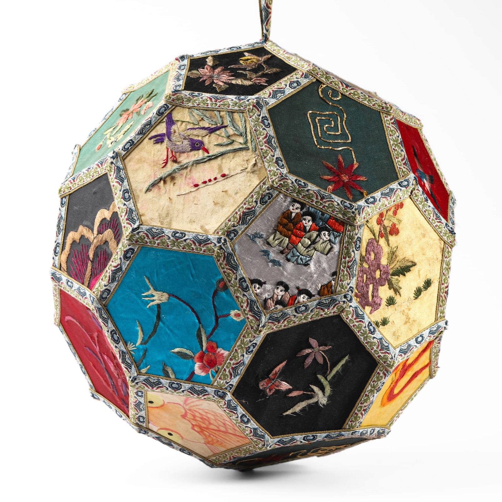 A CHINESE EMBROIDERED SILK BALL-SHAPED HANGING LANTERN: Height: 11 in. (28 cm) Formed as a geometric polyhedron, this elaborately crafted hanging lantern is composed of numerous silk-velvet and satin panels, each hand-embroidered with auspicious motifs