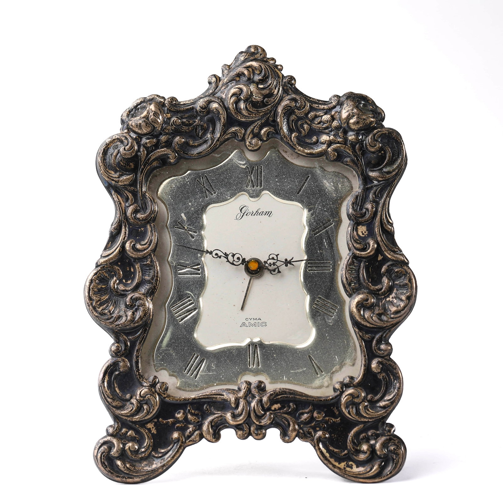 Swiss Silvered Ornate Table Clock by Gorham: Dimensions Width: 3 1/2 in. (8.8 cm); Height: 5 in. (12.8 cm) Description A Gorham table alarm clock with movement by Cyma Watch Co., Switzerland, fitted with an 11-jewel lever escapement. The clock