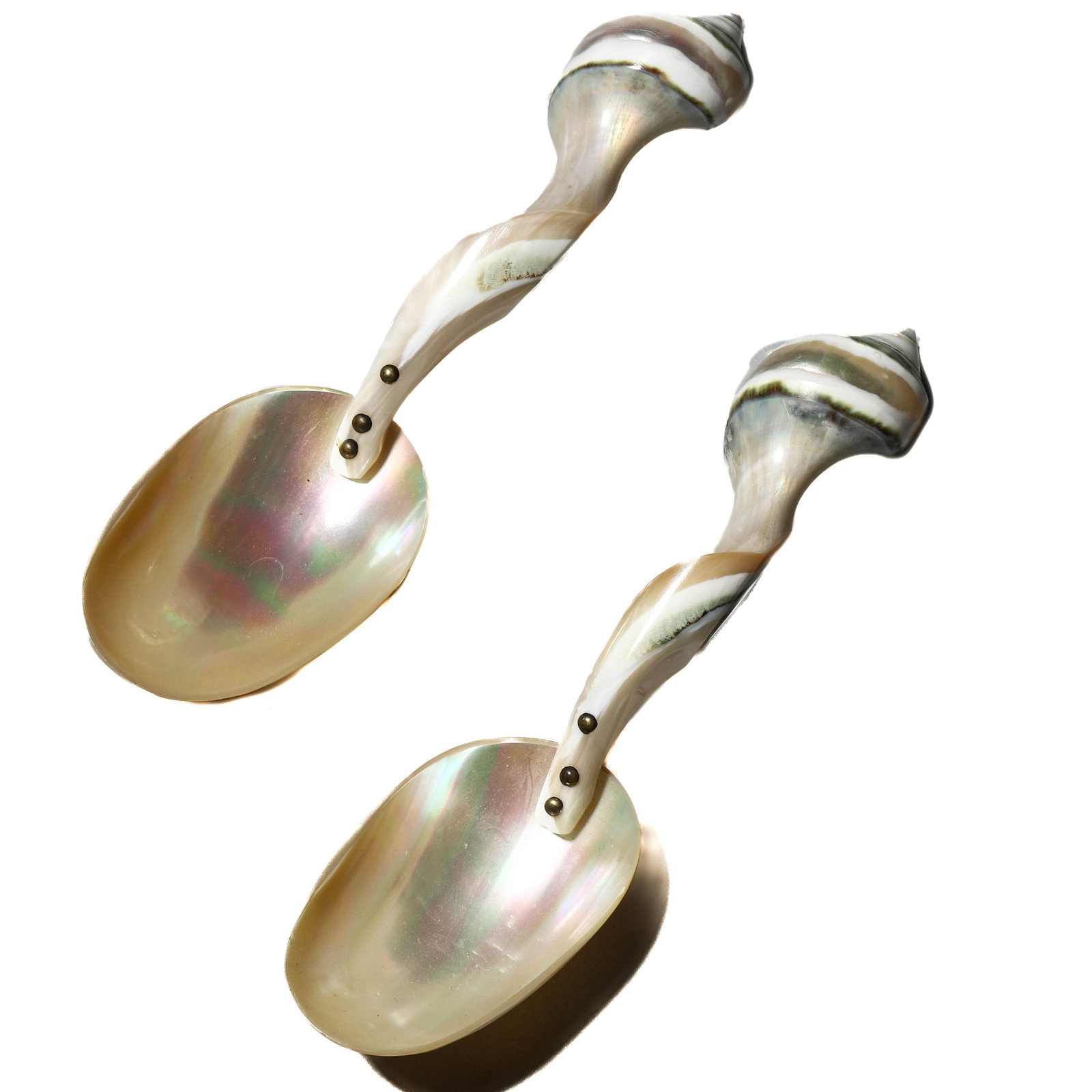 A PAIR OF SHELL-HANDLED MOTHER-OF-PEARL SPOONS, 20TH CENTURY: Dimensions Each 5 7/8 in. (15 cm) long; Combined weight 80.8 g Description A pair of decorative spoons with lustrous mother-of-pearl bowls, each handle formed from a natural conch shell with brass fit