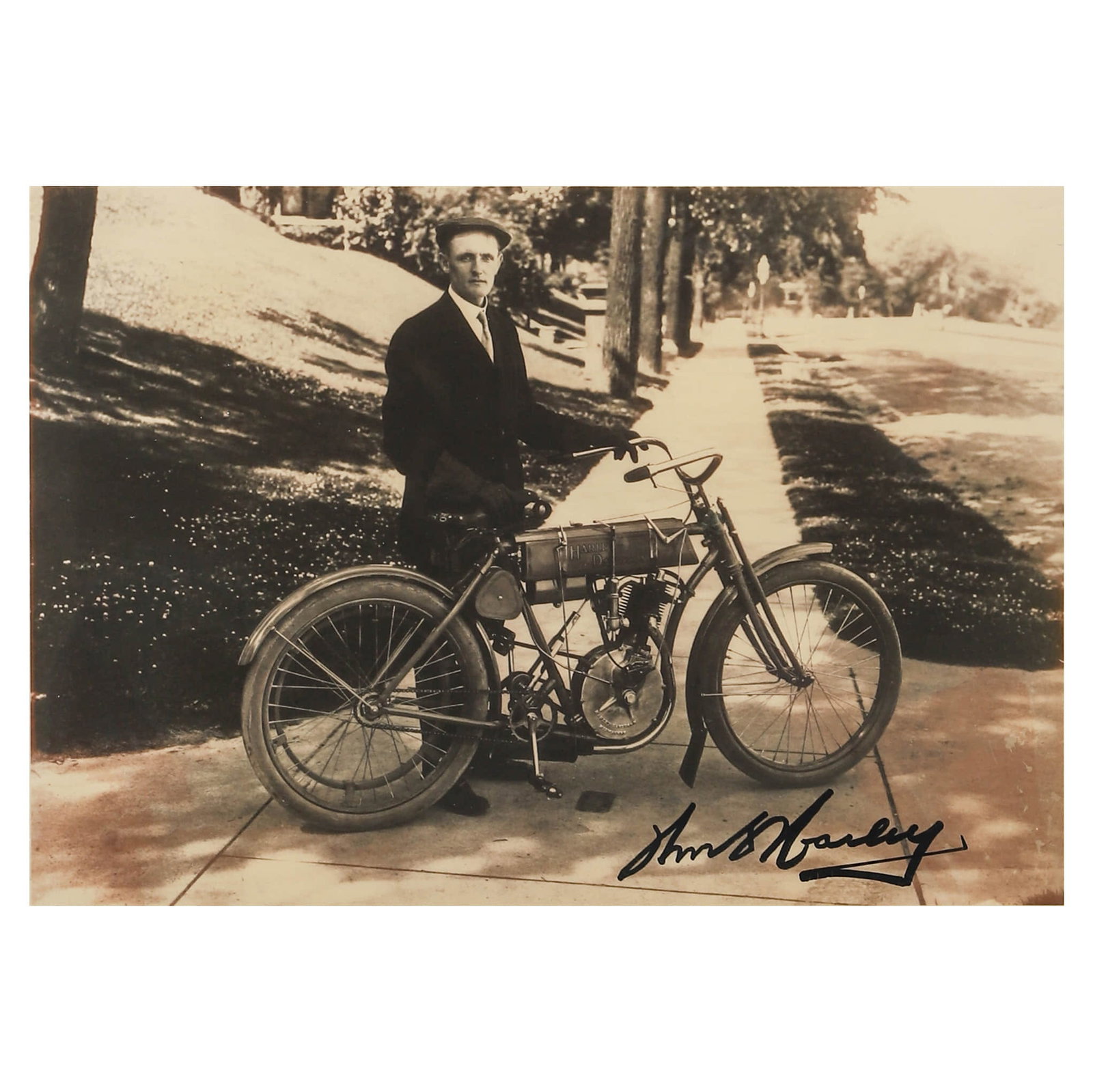 WILLIAM S. HARLEY (1880–1943) SIGNED PHOTOGRAPH WITH EARLY HARLEY-DAVIDSON MOTORCYCLE, CIRCA 1910S: Title: William S. Harley with Early Harley-Davidson Motorcycle Materials: Gelatin silver print Signature: Signed by William S. Harley in ink to the lower margin Size: Photograph: 6 1/8 × 8 3/4 in.