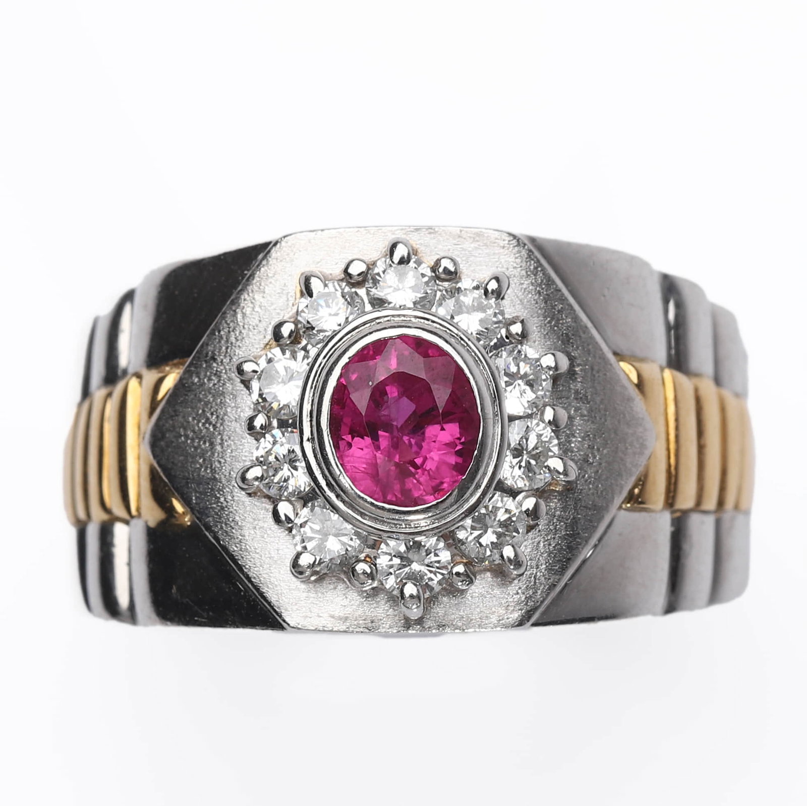 A RUBY AND DIAMOND TWO-TONE GOLD RING: Dimensions Inner diameter: 19.1 mm; Weight: 27.4 g Description A bold two-tone gold ring featuring a central round ruby in a raised bezel setting, surrounded by a halo of small diamonds that add