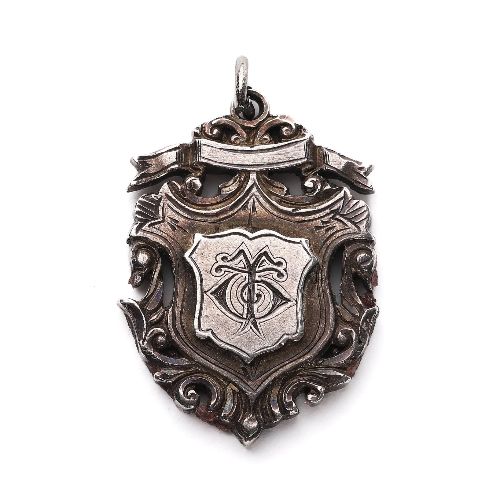 SILVER FOOTBALL MEDAL FOR ASTON VILLA FC, 1898–1899: Dimensions: 1 11/16 × 1 in. (34.1 × 25 mm); Weight: 21.5 g This intricately pierced silver medal features a central cartouche engraved with an ornate monogram and a surrounding scrollwork border.