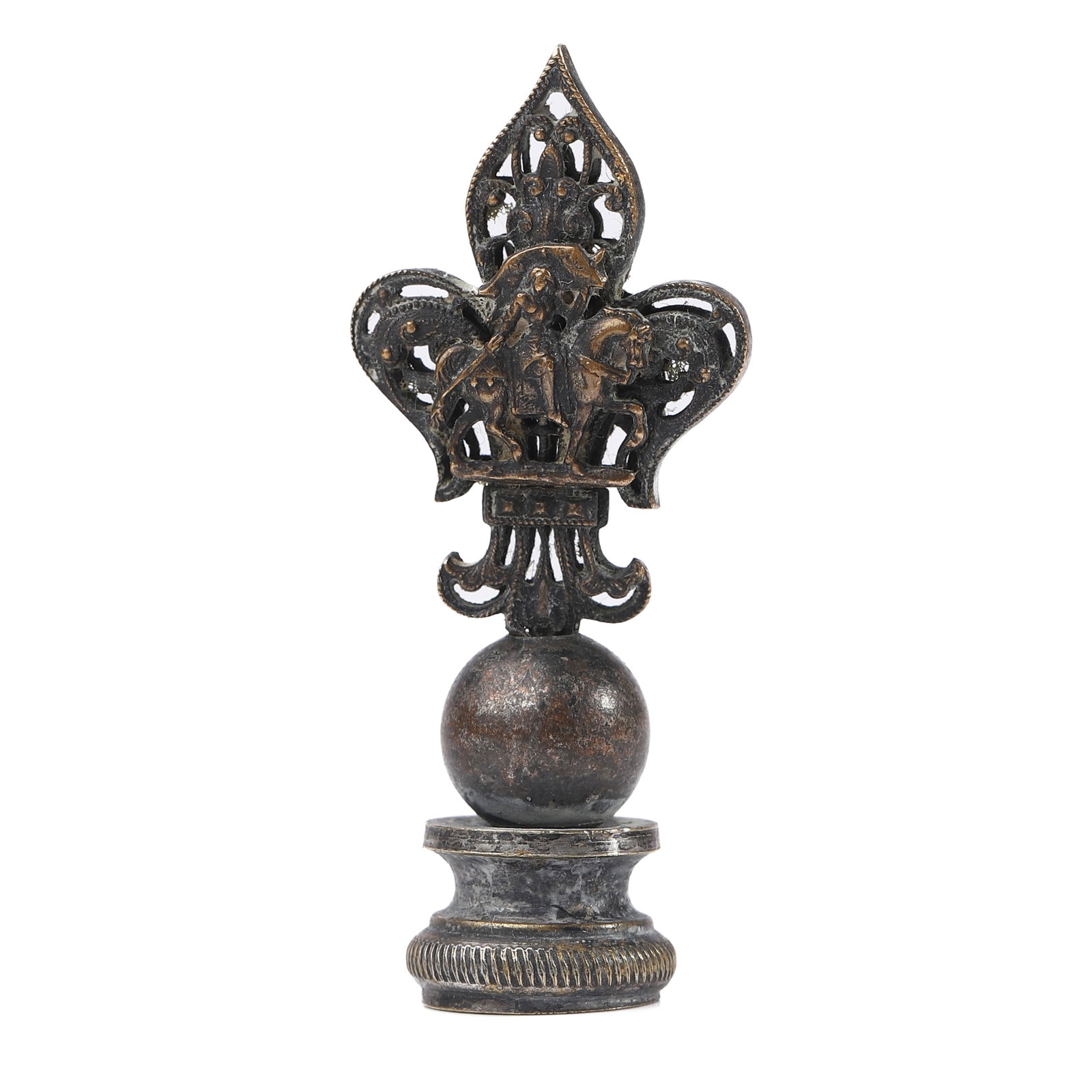 BRONZE FIGURAL SEAL WITH FLEUR-DE-LIS FINIAL: Dimensions Height: 2 1/16 in (5.3 cm); Weight: 17.6 g Description A small bronze figural seal surmounted by an ornate fleur-de-lis finial incorporating miniature figures in relief. The finial rests