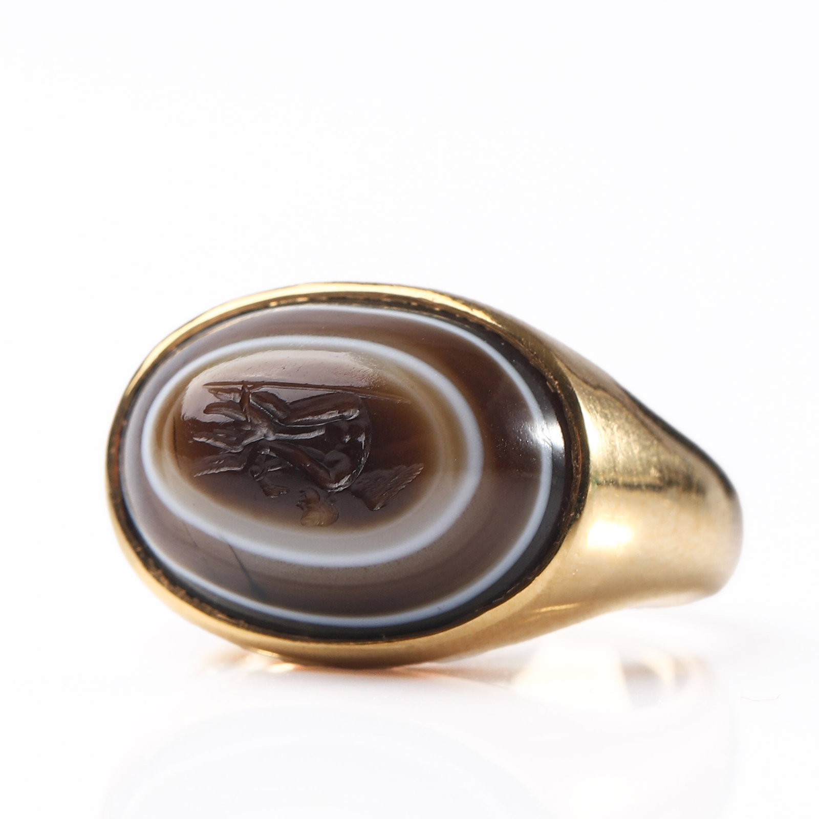 A 22K GOLD RING SET WITH BANDED AGATE.: Dimensions Inner diameter 11/16 in (17 mm); face 5/8 × 7/16 in (15.8 × 11.7 mm); weight 9.4 g. Description The ring is crafted in 22k gold, featuring a smoothly polished oval banded agate cabochon