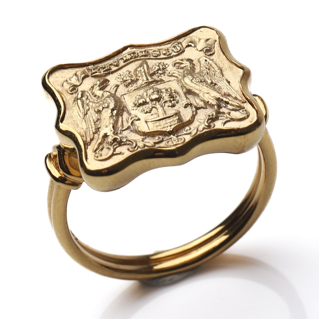 18K GOLD SIGNET-STYLE RING: Dimensions Inner diameter 21/32 in (16.8 mm); Weight: 7 g. Description An 18K gold signet-style ring featuring an engraved heraldic shield with classical supporters in high-relief detail. The