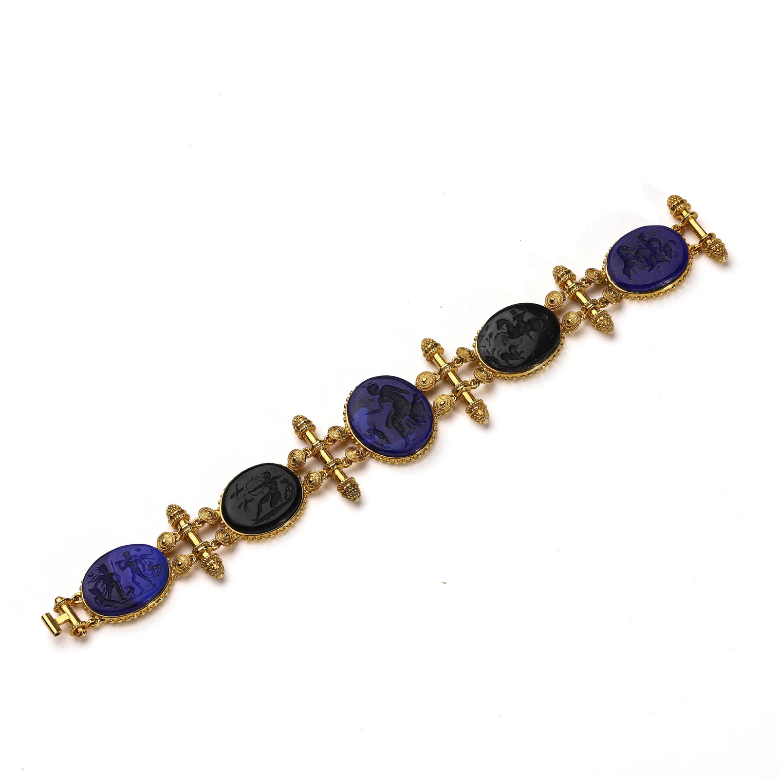 GOLD-BRACELET-WITH-INTAGLIO-GLASS-PLAQUES-IN-ANCIENT-STYLE: Dimensions: Length: 7 1/4 in. (18.5 cm); Weight: 40 g Description: A richly decorated gold bracelet featuring alternating oval black and cobalt blue glass intaglios, each set in finely beaded bezels.