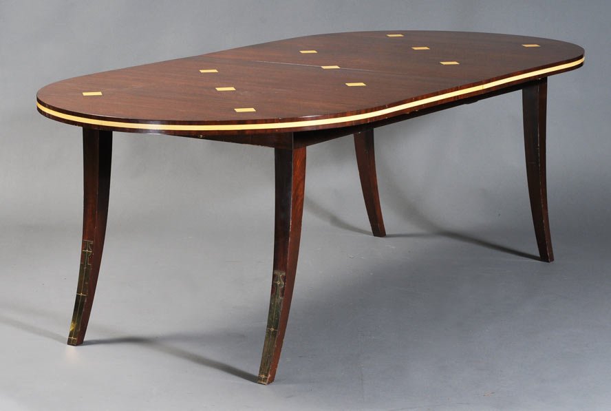Tommi Parzinger Inlaid Mahogany Dining Table: with brass mounts and saber legs has one leaf (21" diameter) 42" x 84" x 29", unsigned mid-20th century estimate 5000/7500 SHIPPING DETAILS: Buyer is responsible for arranging 3rd party shipping