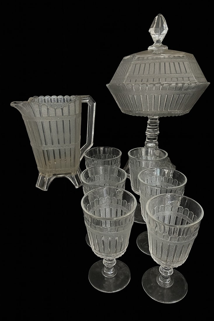 Early 20th-Century Pressed Glass Pitcher, Goblets, and Covered Compote: Charming antique pressed glass table set featuring a tall covered compote, matching pitcher, and six goblets, all displaying a striking paneled and scalloped band pattern.(1) Pitcher, approx. 9?H (chi
