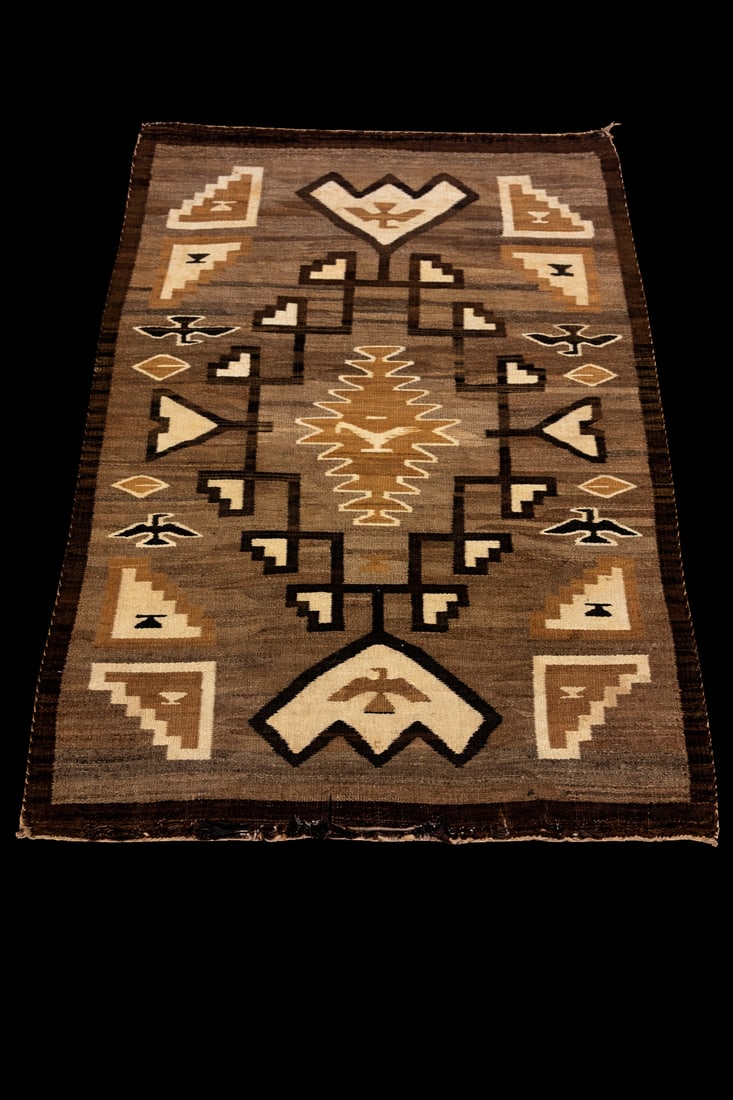 Navajo Handwoven Wool Rug / Textile: likely mid-20th century, featuring classic geometric and Yei-inspired motifs in natural earth tones of brown, tan, cream, and black; handwoven wool construction with traditional banded border; mounted