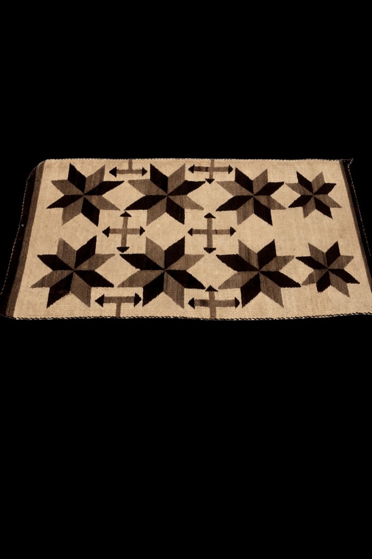 Handwoven Southwest / Navajo-Style Wool Rug: bold repeating eight-point star and directional arrow motifs in shades of black, charcoal, taupe, and cream on a light neutral field; traditional flat-weave construction; wool fibers; rectangular form