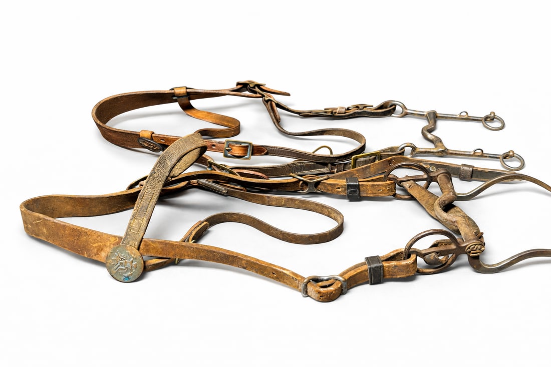 Two Vintage Western Horse Bridles with Bits & Eagle Conchos: Pair of large vintage Western horse bridles, each fitted with metal bits, rings, buckles, and decorative eagle conchos. Leather shows heavy wear, surface cracking, and patina consistent with age and w