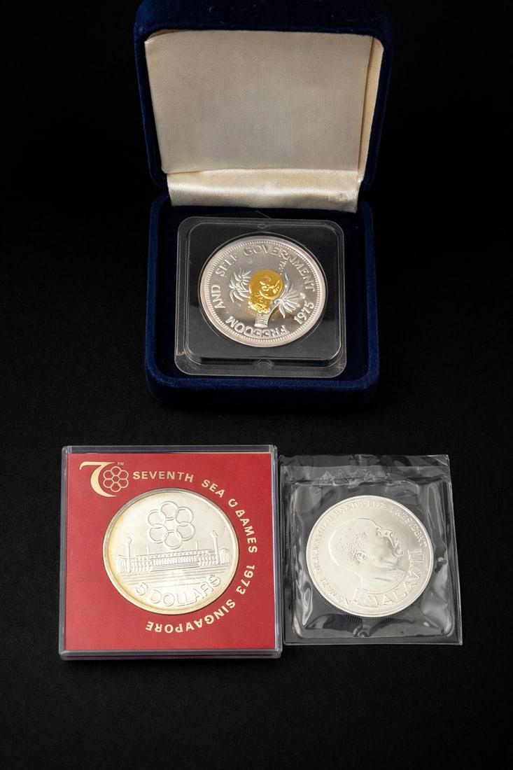 3 Silver Commemorative Coins Solomon Singapore: Group of three commemorative coins including 1975 Solomon Islands $10 Freedom and Self Government coin struck in 24 grams .999 fine silver with gold overlay and original presentation case; 1973 Singap