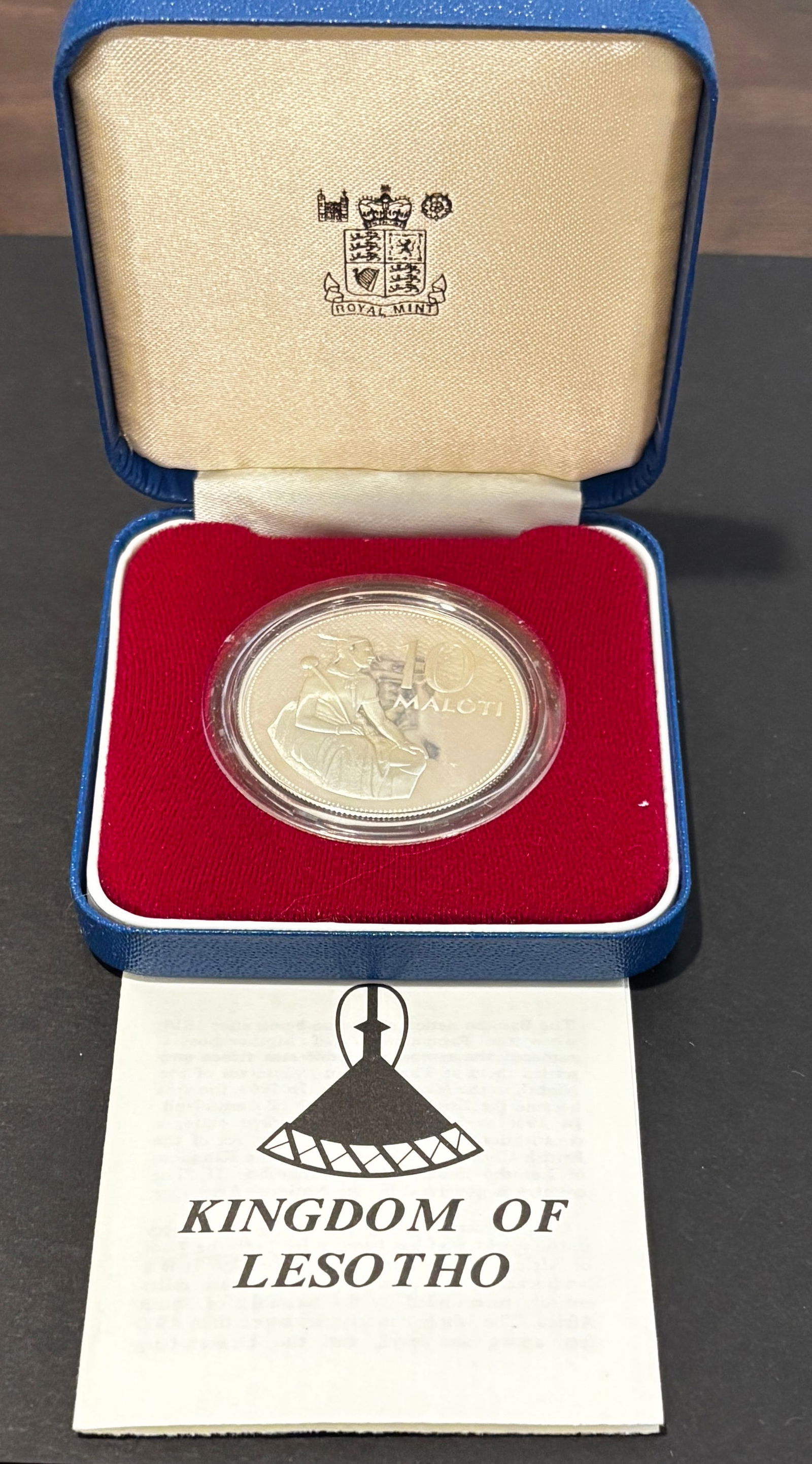 1979 Lesotho H.M. Moshoeshoe II Proof Silver 10 Maloti Coin In Case: 1979 Kingdom of Lesotho proof silver 10 Maloti commemorative featuring a seated traditional Basotho figure on obverse and portrait of King Moshoeshoe II on reverse. Struck by the Royal Mint as a legal