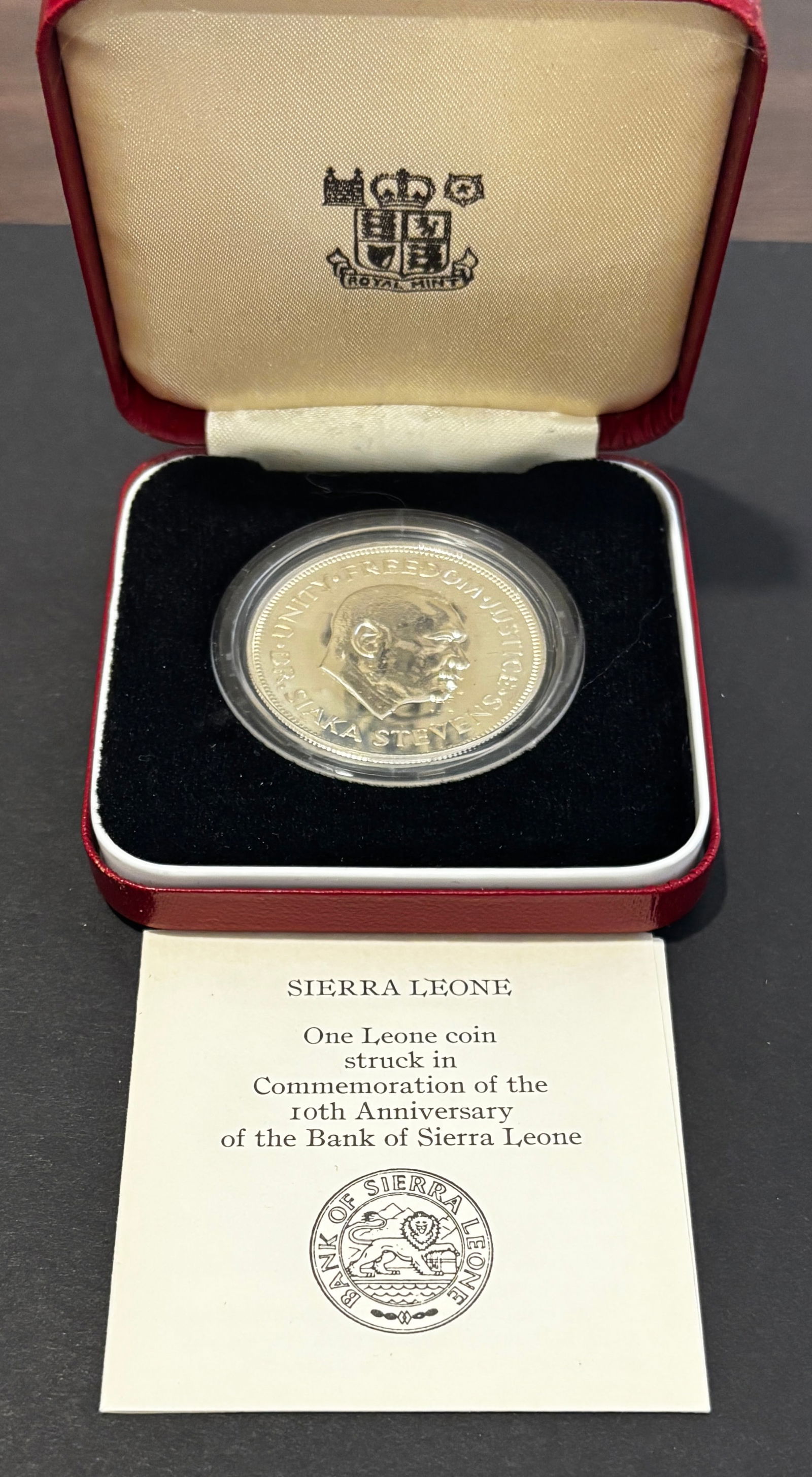 1974 Sierra Leone Siaka Stevens Proof Silver One Leone Coin In Case: 1974 Sierra Leone proof silver One Leone commemorative issued for the 10th Anniversary of the Bank of Sierra Leone, featuring portrait of President Dr. Siaka Stevens with motto “Unity, Freedom,