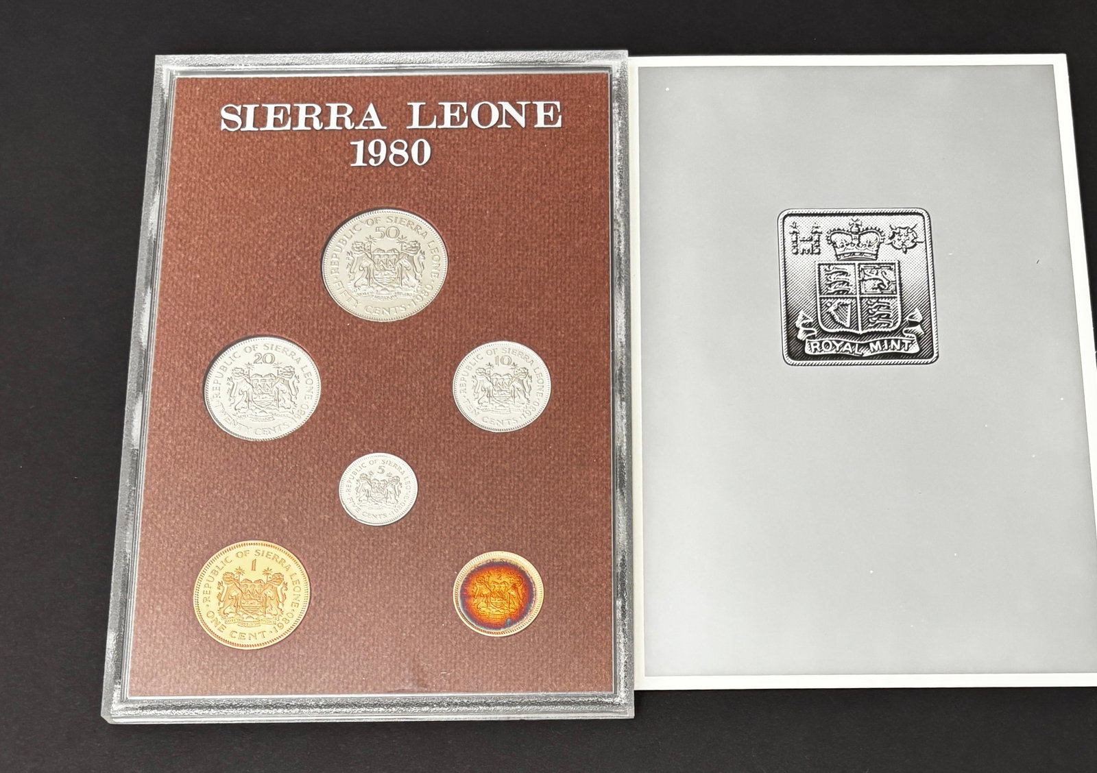 1980 Sierra Leone Royal Mint Proof Coin Set In Original Holder And Folder: Official 1980 Republic of Sierra Leone proof coin set struck by the Royal Mint and housed in the original presentation holder with accompanying Royal Mint folder. The set features the portrait of Siak