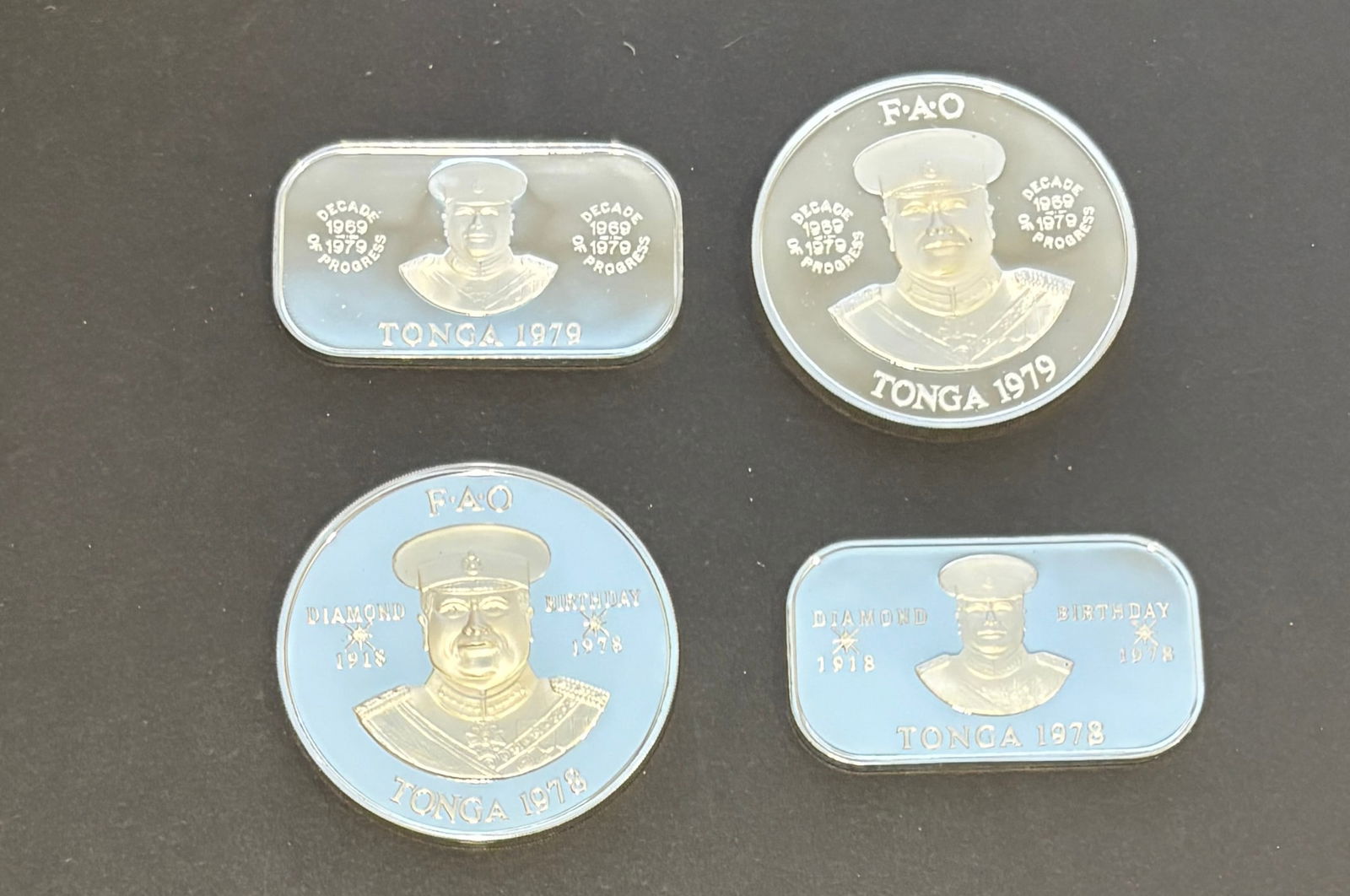 1978–1979 Tonga FAO Commemorative Proof Coin Group: Group of four Tonga FAO (Food and Agriculture Organization) commemorative proof coins dated 1978 and 1979, including round and rectangular issues. Designs feature King Taufa’ahau Tupou IV portraits,