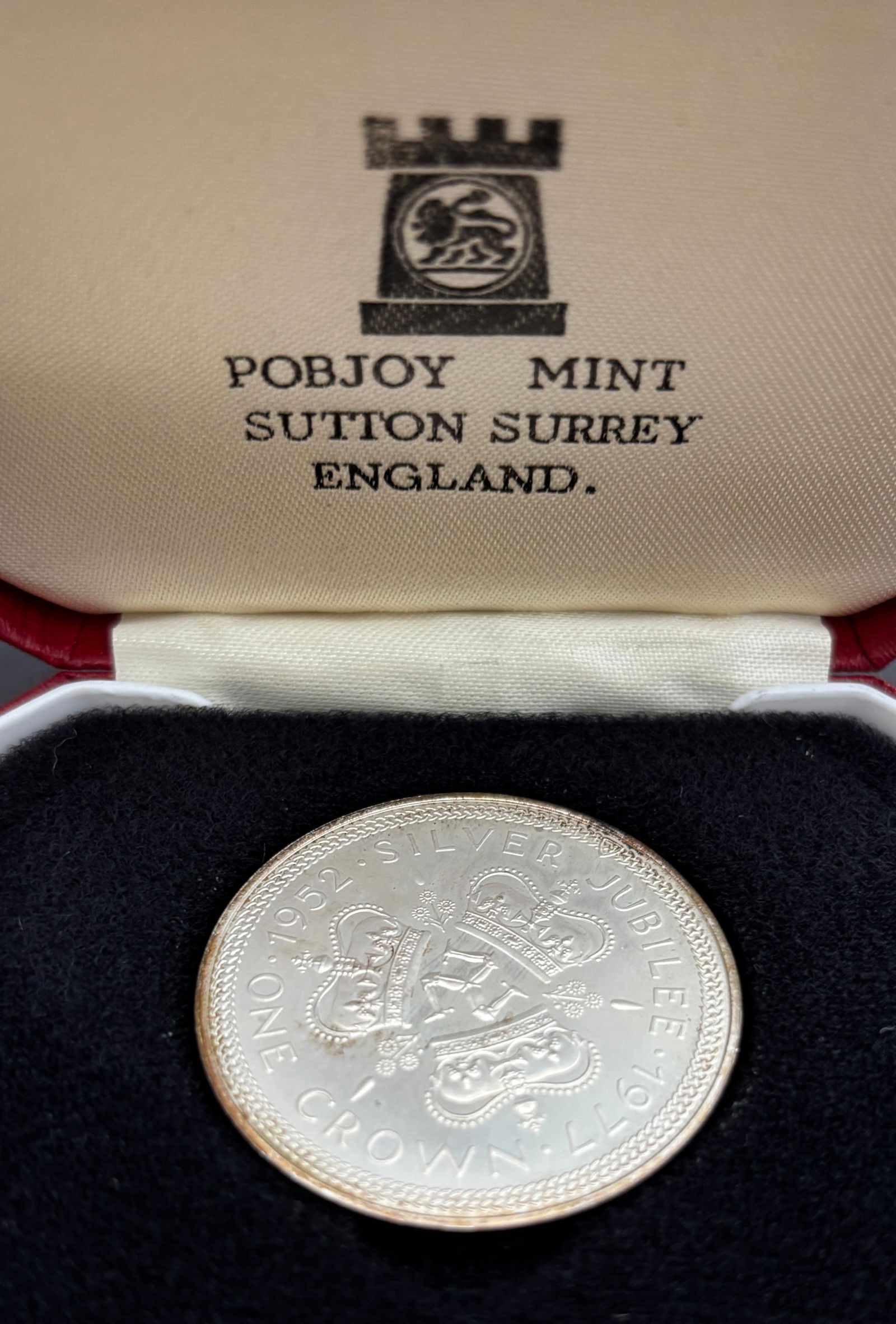 1977 Isle of Man Silver Jubilee One Crown Proof Coin – Pobjoy Mint: 1977 Isle of Man One Crown Silver Jubilee proof coin issued to commemorate the Silver Jubilee of Her Majesty Queen Elizabeth II (1952–1977), struck in sterling silver by the Pobjoy Mint, Sutton Surr