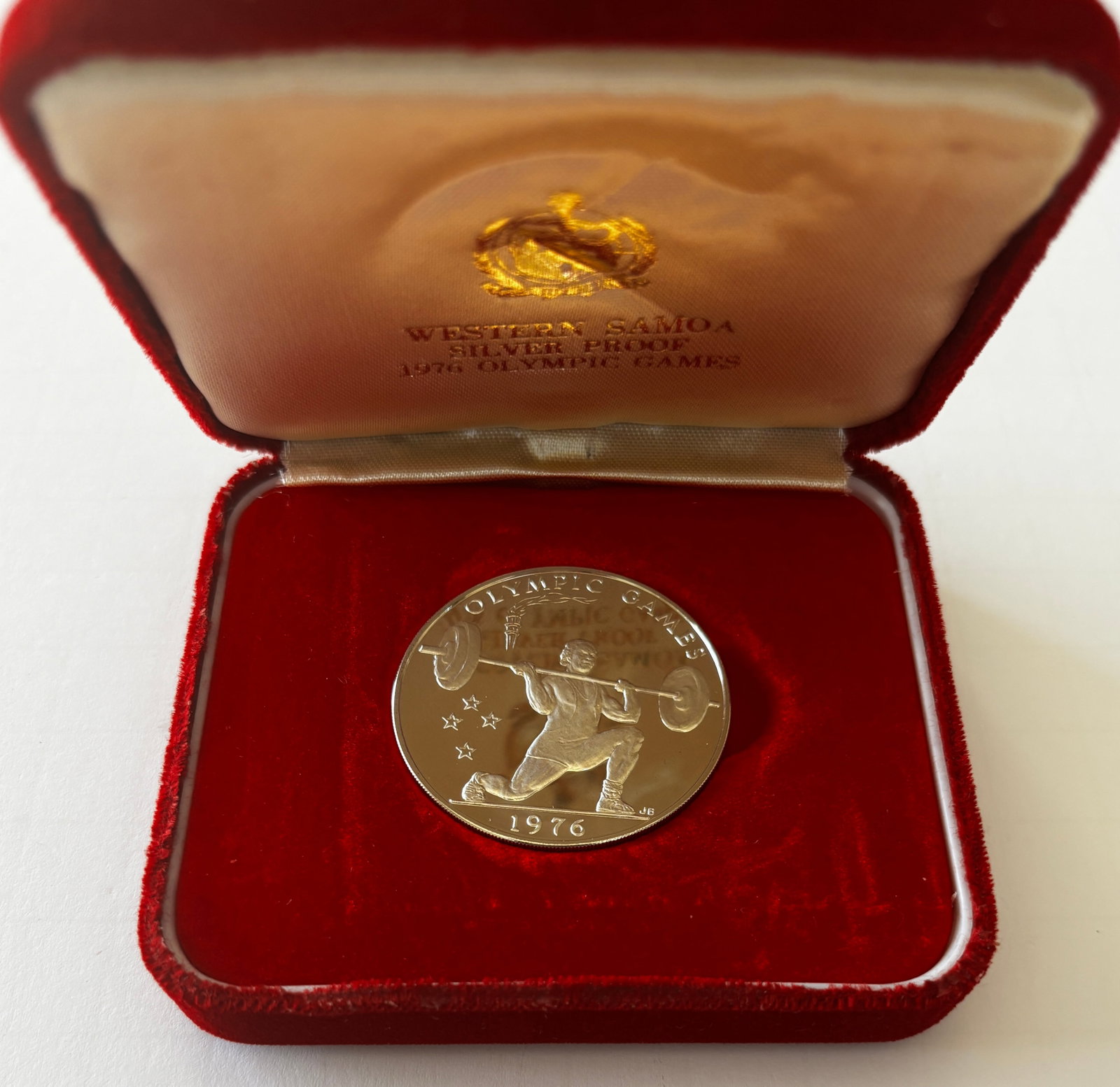 1976 Western Samoa $1 Silver Proof Coin: 1976 Western Samoa $1 silver proof coin commemorating the Olympic Games, struck in fine silver and issued in limited mintage, featuring Olympic weightlifting design and national crest, presented in or