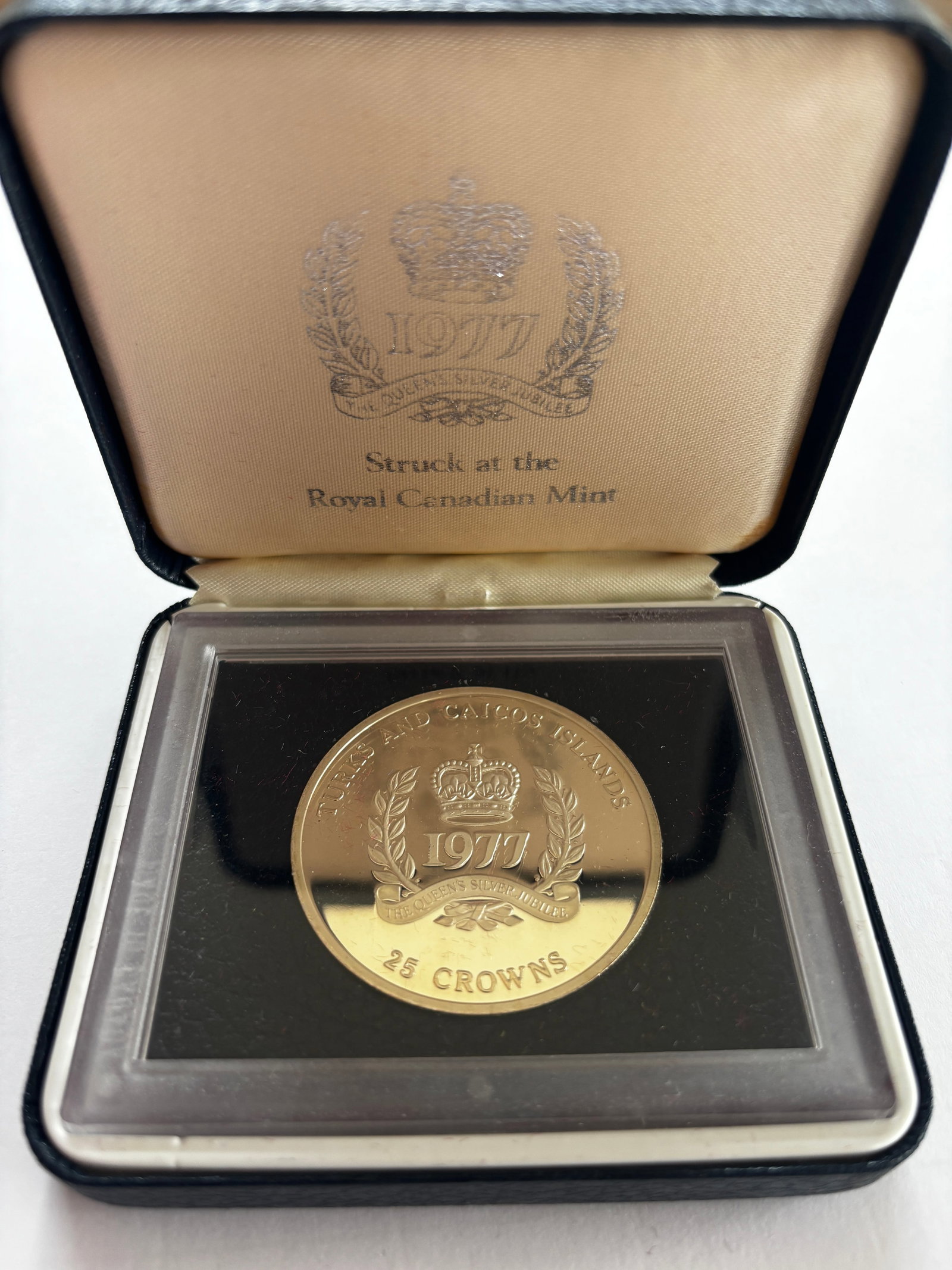 1977 Turks & Caicos 25 Crowns Silver Jubilee Coin: 1977 Turks & Caicos Islands 25 Crowns commemorative coin struck at the Royal Canadian Mint to honor the Silver Jubilee of Queen Elizabeth II. Coin features a crowned “1977” jubilee design with