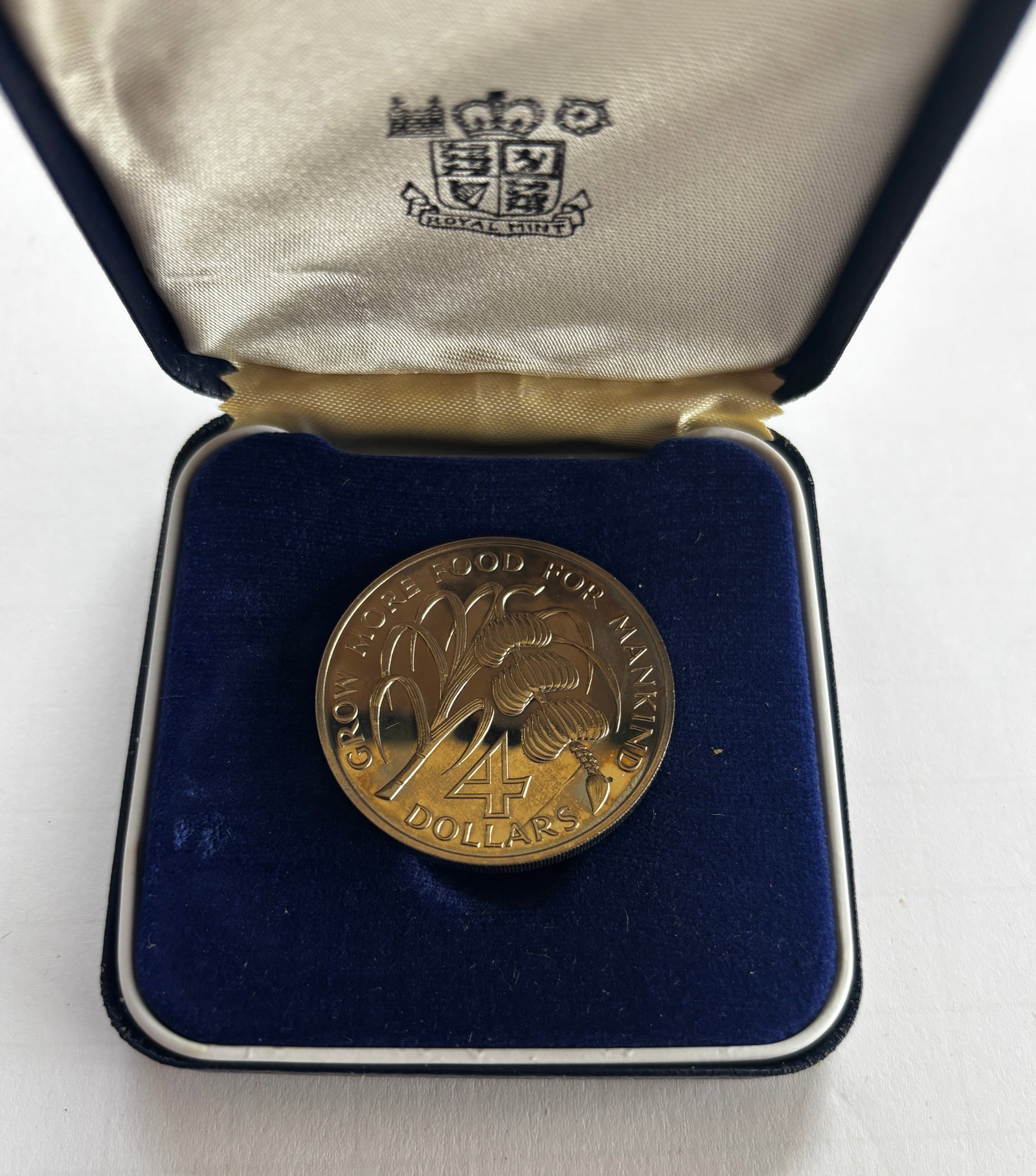 1970 Grenada Proof $4 Coin: 1970 Grenada proof four-dollar commemorative coin issued for the inauguration of the Caribbean Development Bank, housed in the original Royal Mint presentation case. Coin features stylized agricultura