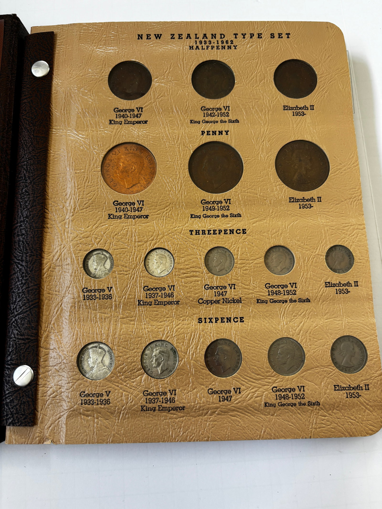 New Zealand Type Coin Album, Partially Complete Collection, George V–Elizabeth II: Vintage New Zealand Type Set album containing an assortment of New Zealand coinage spanning the reigns of George V, George VI, and Elizabeth II. Collection includes examples of Halfpenny, Penny, Three