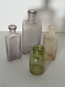 Antique Medicine Bottle Lot Eastman Rochester NY Crab Apple Cream Arnicated Eureka + Green Glass: Four antique medicine bottles including Eastman Rochester NY (lilac), Crab Apple Cream Brand (lilac), Arnicated Eureka Cream (clear), and unmarked green utility bottle; sizes approx. 4"–7"H