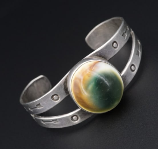 Harvey Era Vintage Silver Bracelet Operculum Shell Cuff Hand Stamped 6.5" BS2962: This vintage Fred Harvey Era cuff bracelet is crafted of sterling silver. It features a polished operculum shell set at the center with hand stamped sun and arrow accents. The natural patina showcases