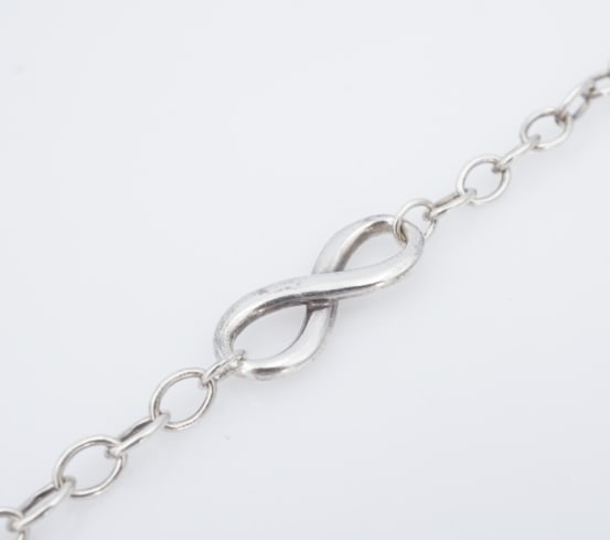 Tiffany & Co. Infinity Chain Link Bracelet Sterling Silver 7" Retired BS3178: This retired Tiffany & Co. bracelet features a cable link chain design with a classic infinity charm fixed in the center. The bracelet fastens securely with a large lobster clasp. The perfect gift for