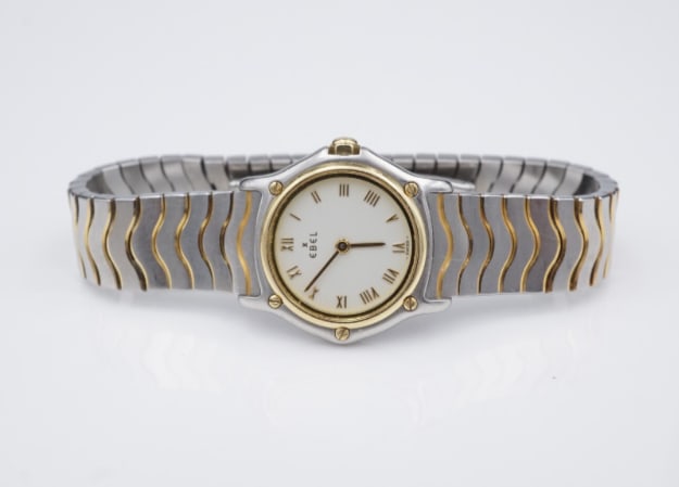 Ebel Classic Sport Wave White Dial 23mm 2-Tone SS 18k Bracelet 1057901 6" W1110: Guaranteed authentic Ladies Ebel Classic Wave watch. This classic watch features a solid stainless-steel case with 18k accents, unique 2-tone wave link bracelet, sapphire crystal, and white dial with