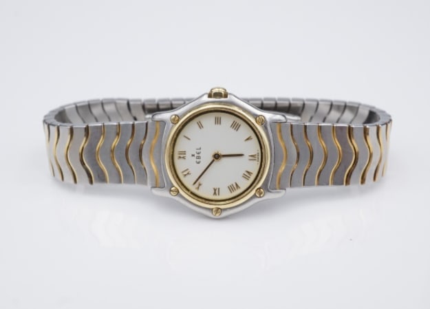 Ebel Classic Sport Wave White Dial 23mm 2-Tone SS 18k Bracelet 1057901 6" W1110: Guaranteed authentic Ladies Ebel Classic Wave watch. This classic watch features a solid stainless-steel case with 18k accents, unique 2-tone wave link bracelet, sapphire crystal, and white dial with 