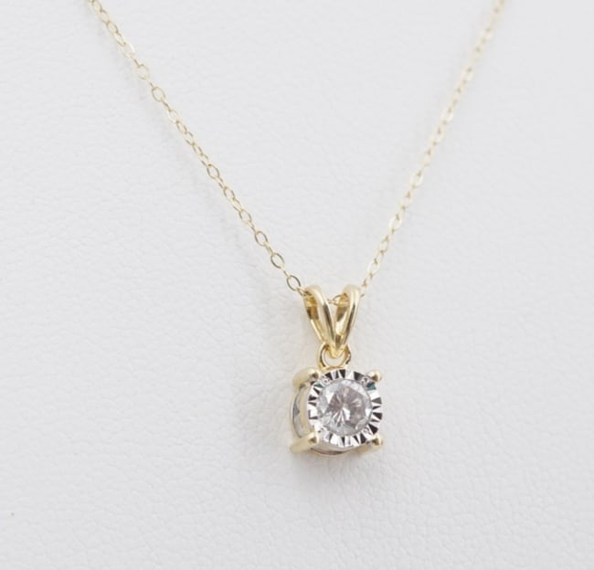 14k Natural Diamond Solitaire Pendant Necklace Yellow Gold 18" ZEI Zales NG1803: This gorgeous Zales necklace centers on a stunning natural 4mm diamond solitaire in a classic illusion setting with additional diamond accents set on each side of the basket. Suspended from a supple 1