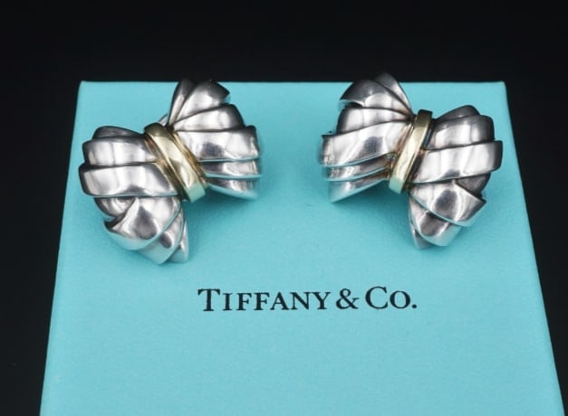 Tiffany Bow Ribbon Earrings Sterling Silver 18k Yellow Gold Clip ES2341: These beautiful statement earrings feature solid sterling silver folded ribbon bows, accented in the center in 18k yellow gold. The earrings fasten easily with clip-on closures for non-pierced (or pie