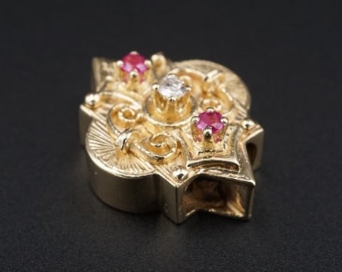 14k Gold Diamond Pink Sapphire Slide Charm 0.7" Kurt Goldschmidt Vintage CHS2155: This beautiful vintage slide charm from Kurt Goldschmidt Jewelers features a natural white diamond flanked by vibrant pink sapphire accents atop an ornate 14k yellow gold frame with delicate scroll de
