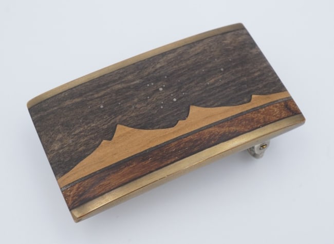 Kenneth Reid Artisan Wood Belt Buckle Inlay New Mexico 2.6" M2063: This awesome belt buckle features an inlaid design in multiple wood tones, showing a Western mountain scene at night with a starry sky. This beautiful design is sure to make a statement! Metal Type:Br