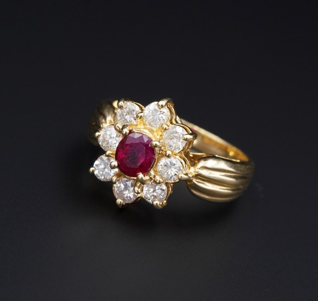 18k Yellow Gold 1.5 ctw Oval Ruby Diamond Halo Flower Ring Size 5.75: This beautiful ring features an oval cut ruby surrounded by a sparkling halo of diamonds creating a floral design. All set in solid 18k yellow gold atop a tapered polished band with fluted shoulders. 