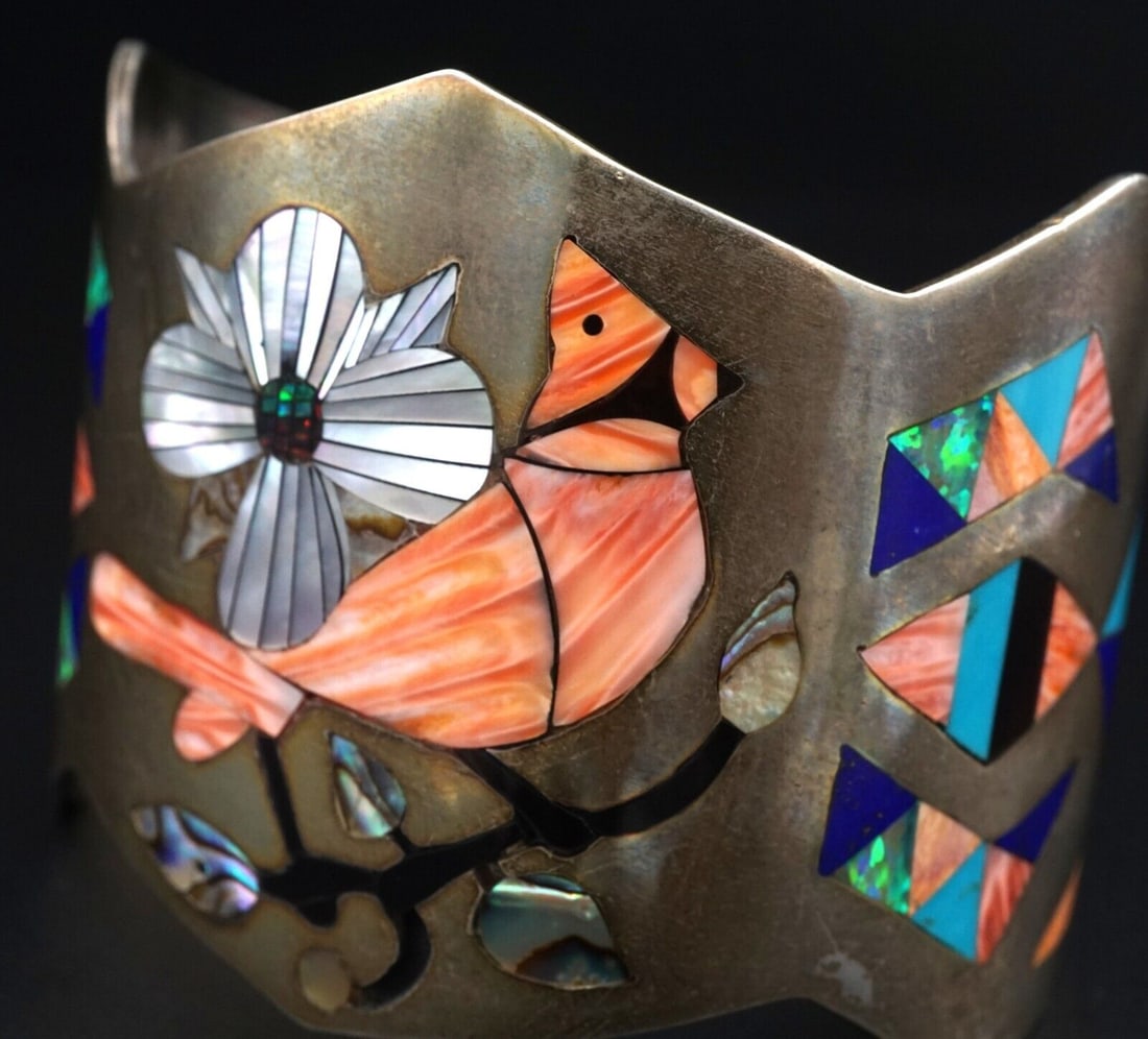 Zuni Cuff Bracelet Sterling Cardinal Shell Opal Inlay Signed SB Banteah BS3029: Hand crafted by Zuni artisans, this beautiful vintage cuff bracelet features a vibrant spiny oyster Cardinel set amongst flowers, with elaborate inlaid sections of turquoise, purple spiny oyster, onyx