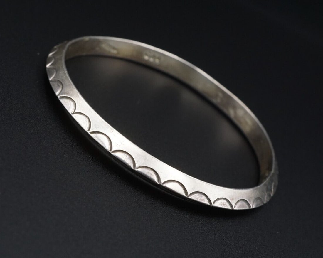Navajo Sterling Silver Bangle Bracelet Christopher J Hoskie 8" Stamped BS2918: This handmade sterling silver bangle displays beautiful hand-stamped detailing around the entire knife-edge cuff. Crafted of solid sterling silver with a substantial 6.2 mm width, this statement piece