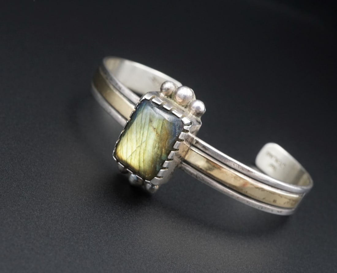 Navajo Alvin A Monte Sterling Silver 14k Labradorite Cuff Bracelet 6.5" BS2604: This detailed cuff features a slim construction crafted of solid sterling silver. The bracelet has a single natural labradorite stone bezel set with bead accents. Thick 14k gold plates accent the arms