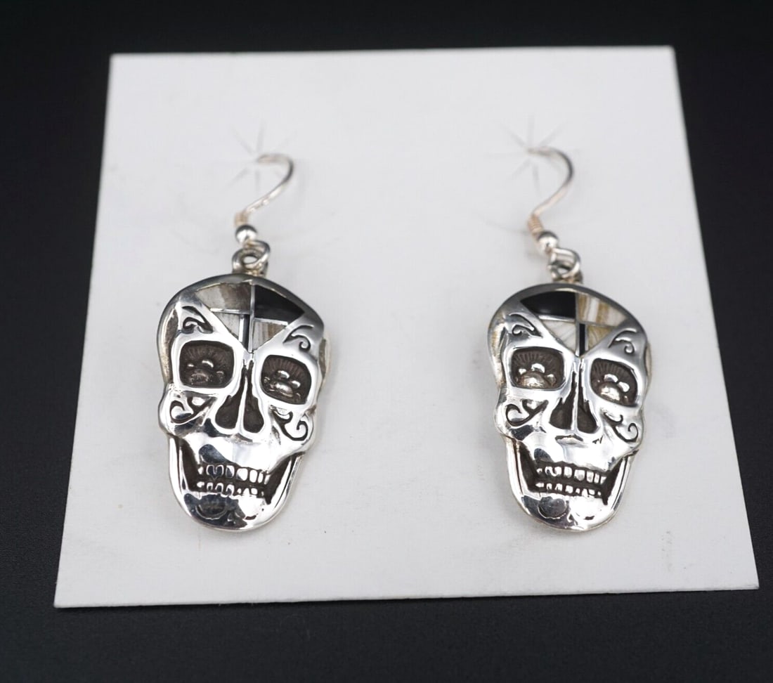 Navajo Skull Dangle Earrings Inlay Sterling Silver 2" Silver Smoke Onyx ES2672: These Navajo artisan earrings each feature a detailed sterling silver skull design embellished with inlaid onyx and shell accents on the crown. The earrings secure with sturdy hooks for pierced ears. 