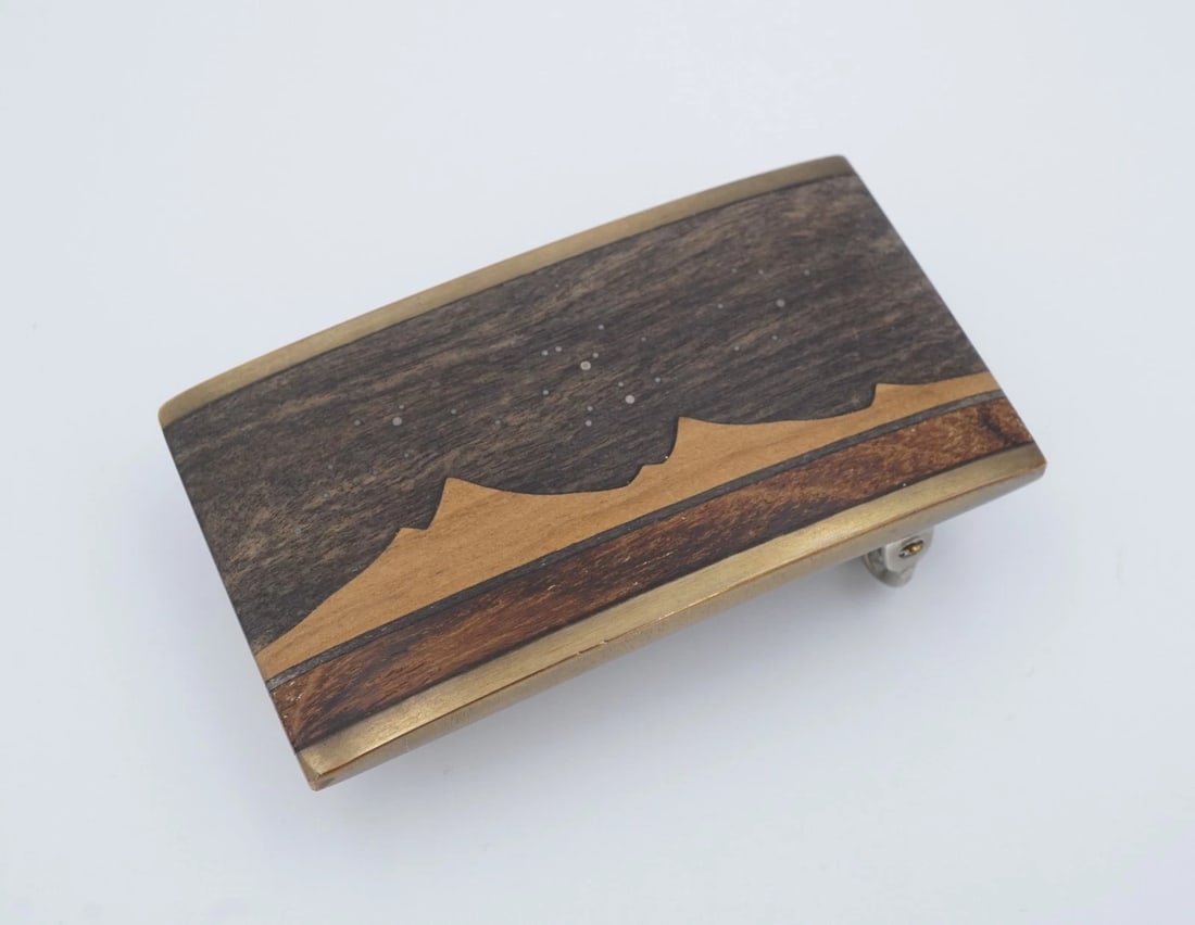 Kenneth Reid Artisan Wood Belt Buckle Inlay New Mexico 2.6" M2063: This awesome belt buckle features an inlaid design in multiple wood tones, showing a Western mountain scene at night with a starry sky. This beautiful design is sure to make a statement! Metal Type: B