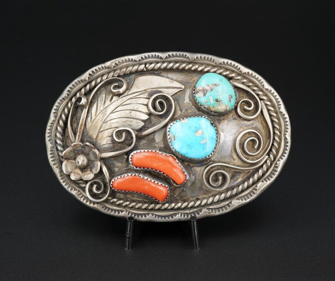 Vintage Navajo Belt Buckle Sterling Silver Turquoise Coral 3D 1960s 3.3" M1798: This large mid-century sterling silver belt buckle features two colors of gorgeous natural turquoise with vivid red-orange coral accents nestled between 3D squash blossom and swirled details. Roping a