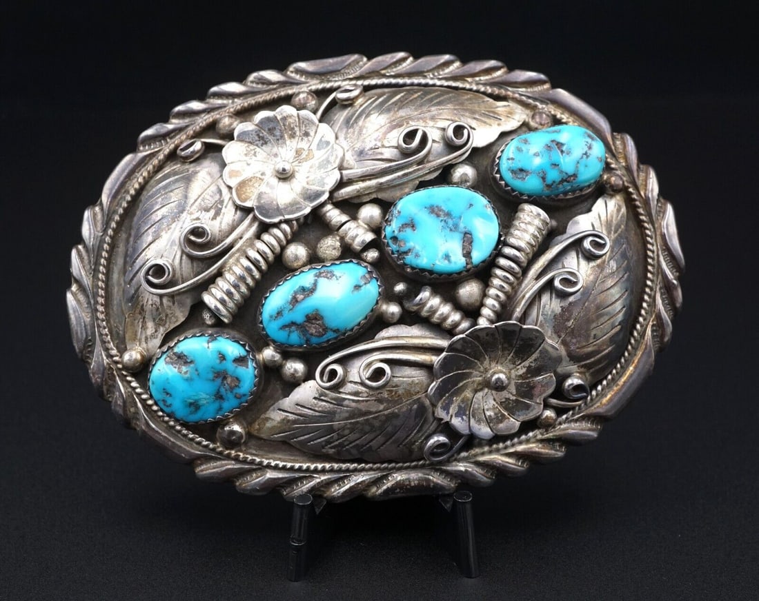 Vintage Navajo Sterling Silver Turquoise Belt Buckle 3.4" Fred James M1867: This large mid-century sterling silver belt buckle features four gorgeous natural turquoise nestled between raised floral, feather, and swirled details. Hand-stamped detailing ring the edges of the bu