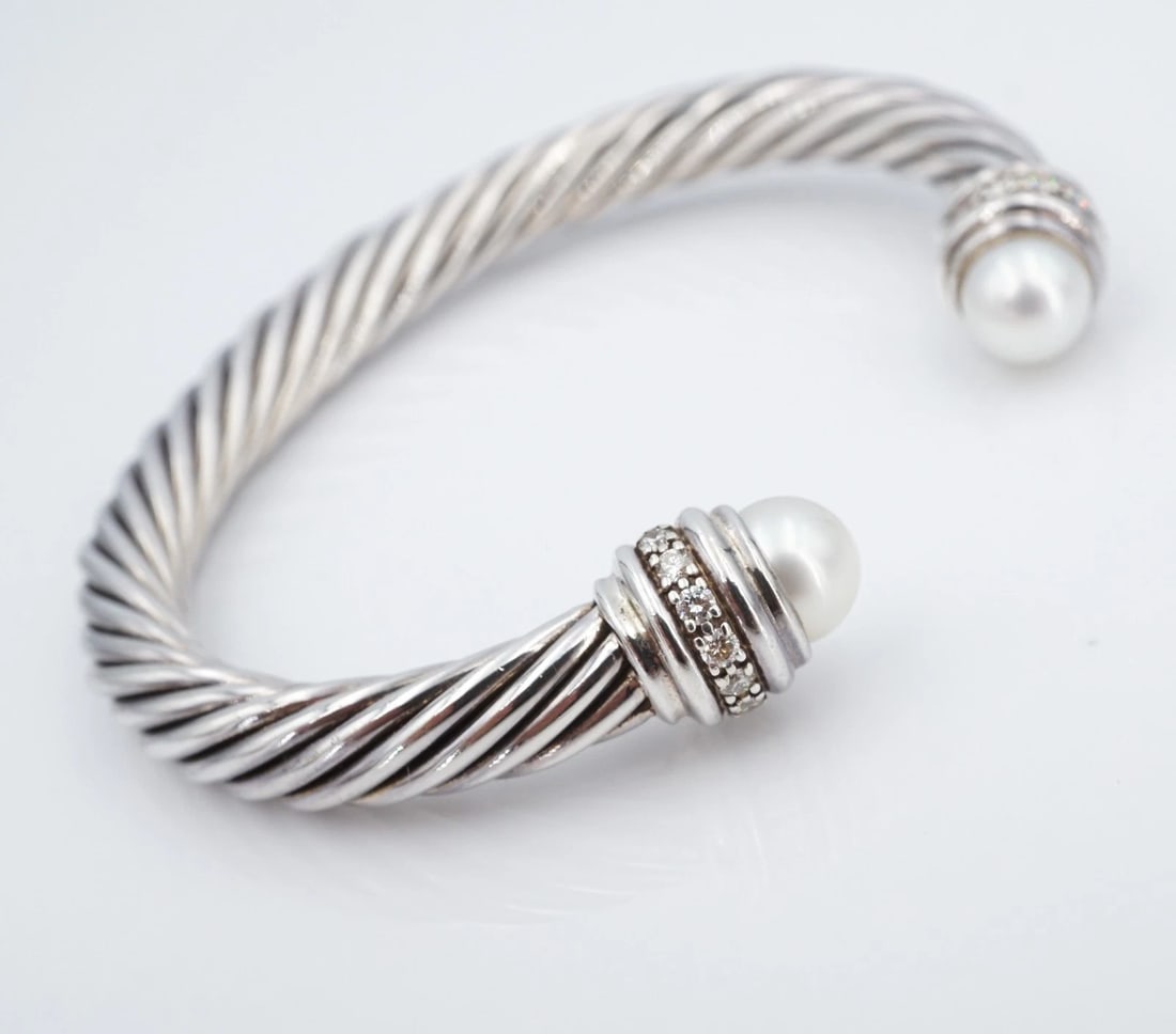 David Yurman Classic Cable Diamond Pearl Bracelet Sterling Silver 7mm BS3197: This retired bracelet from David Yurman features the iconic cable classic cuff design crafted in solid sterling silver with pave diamond accents and pearl finials on either end. Metal Type: Sterling S